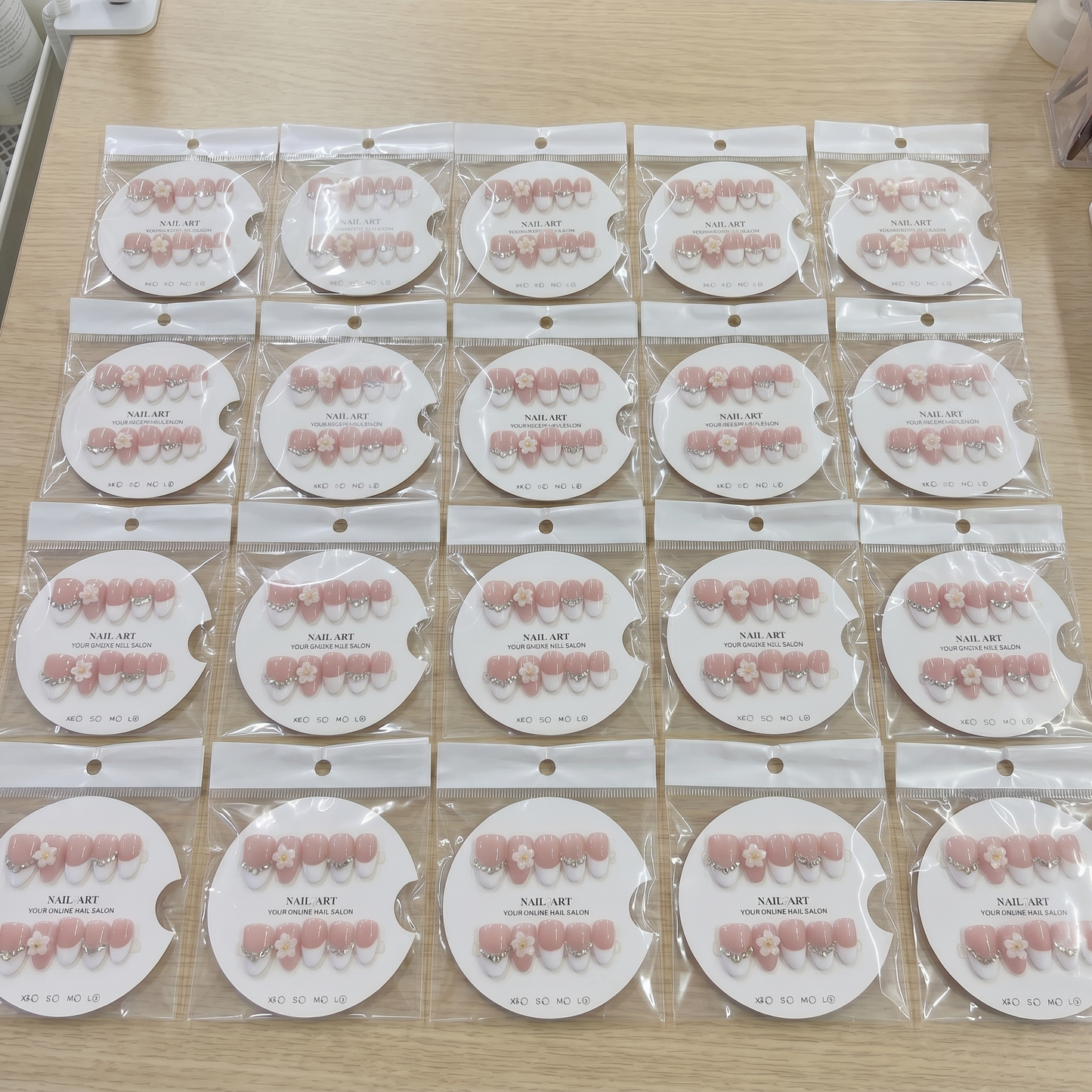 A complete set of almond-shaped white French tip press on nails with 3D daisies and rhinestones, organized by size on display cards.