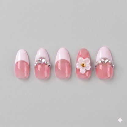 Elegant almond-shaped white French tip press on nails on a nude pink base, featuring a large 3D white daisy and sparkling rhinestone accents.