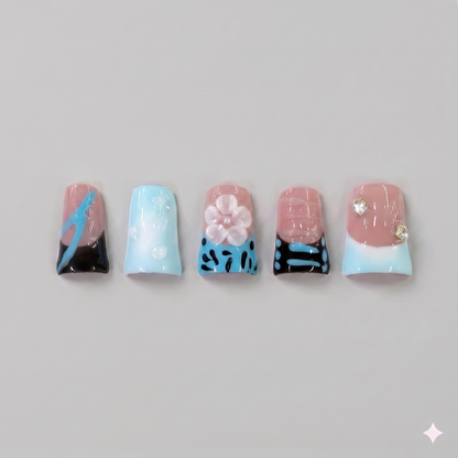 Blue abstract square press on nails featuring edgy black patterns, a soft baby blue base, and detailed 3D pink blooming flowers with rhinestones.