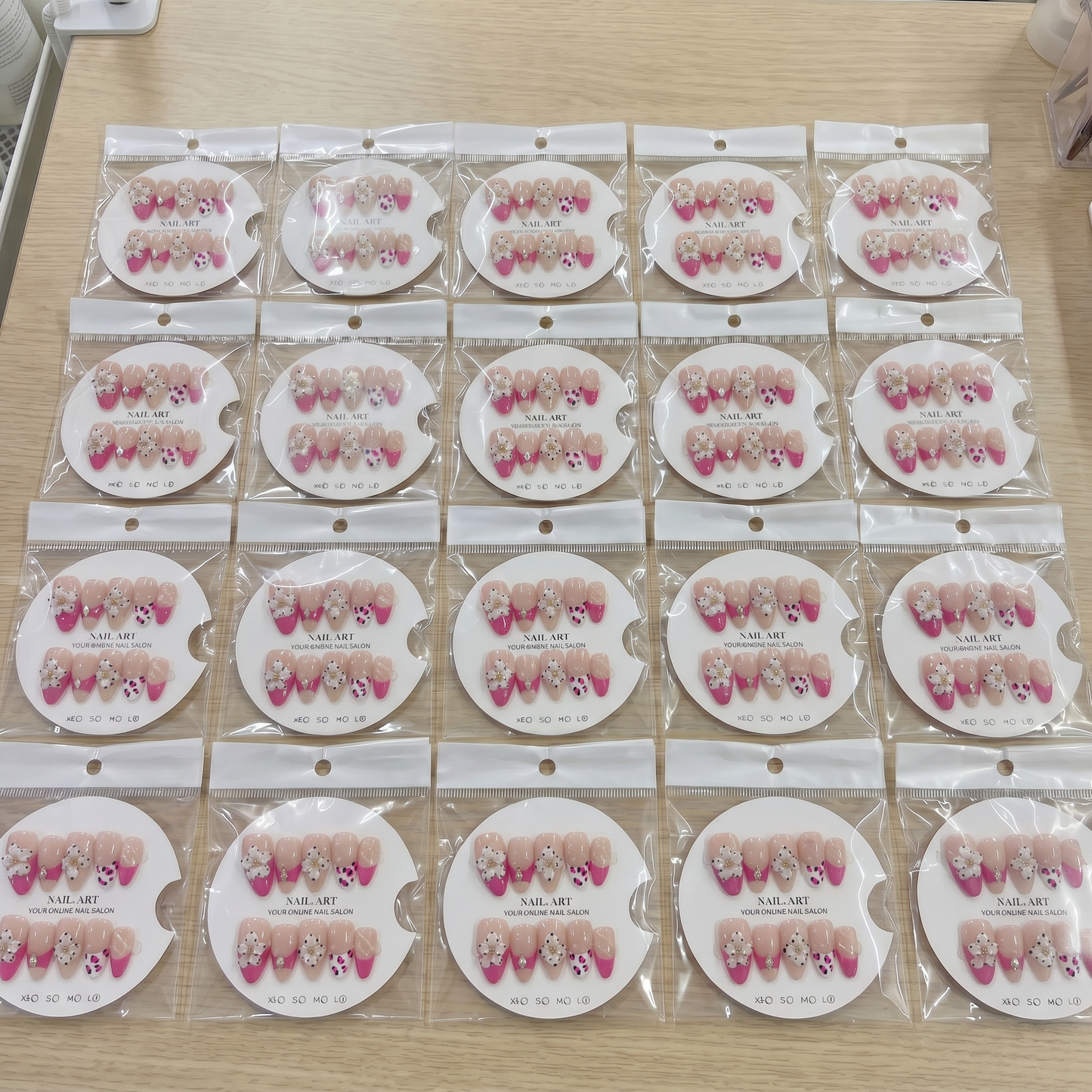 Full set of hot pink floral French tip almond press on nails displayed on size cards.
