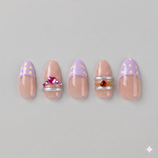 Lavender gold swirl almond press on nails featuring soft French tips, elegant gold chrome swirls, and sparkling pink and red rhinestones.