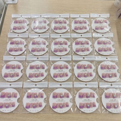 Full set of plum purple French tip rhinestone square press on nails displayed on size cards.